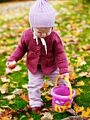 Toddler with bucket in autumnal garden