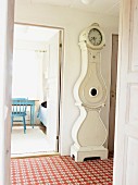 Antique, white longcase clock in tiled hallway