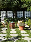 Gartenfläche im Schachbrettmuster mit filigranen Gartenstühlen und -tisch aus rostigem Metall