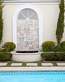 Rundbogenfenster mit Steinplatten-Mosaik und kleinem Brunnen