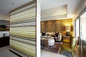 Partition wall with coloured stripes screening lounge with fifties armchairs and modern couch in open-plan interior