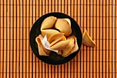 Fortune cookies in a bowl on a bamboo mat