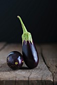 Two baby aubergines on a wooden tabletop