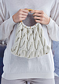 Hand-knitted bag held in woman's hands
