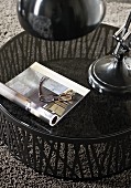 Open book and reading glasses on round table with glass top on grey rug