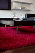 Coffee table with metal legs on red woollen rug