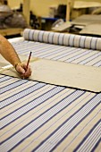 Upholstery cutting pattern on bolt of striped cloth in furniture maker's workshop