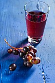 Red wine grapes and grape juice on a bllue wooden tabletop