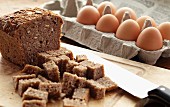 Loaf of Nut Bread with Pieces Cut in Large Cubes and a Carton of Eggs