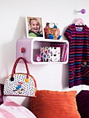 Child's bedroom (detail) with shelf, scatter cushions, bag and child's clothes
