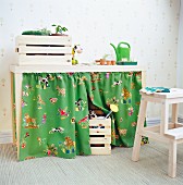 Child's potting table with storage space behind colourful curtains