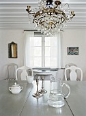 White interior with low ceiling, chandelier & dining table