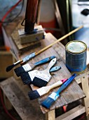 Pot of paint and various paintbrushes on wooden stool