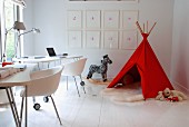 Two workstations with modern shell chairs at desks on castors and toys around red teepee in corner of room