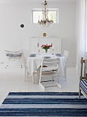 Swedish-style dining room in white & blue with set table & chandelier
