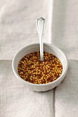 Coarse-grained mustard in a bowl with a spoon