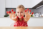Girl putting raspberries on fingers