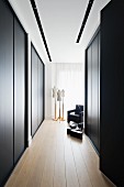 Elegant dressing area with floor-to-ceiling, black fitted wardrobes; tailors' dummies and black armchair in background