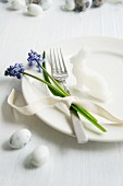 A place setting decorated with a radish rabbit and grape hyacinths
