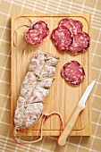 Sliced and Whole Salami on Cutting Board with Knife