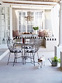 Verspielte Drahtstühle und Tisch mit Glasplatte auf romantischer Landhaus-Terrasse