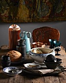 Eclectic collection of soup tureens, bowls, glasses and vases on rustic wooden table