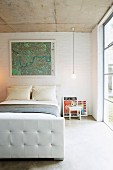 Gerahmte Landkarte über französischem Bett in einfachem Schlafraum mit grosser Fensterfront