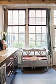 Rustic bench below lattice window next to modern kitchen counter