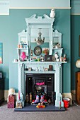 White-painted, nostalgic fire surround with mirror decorated with hotchpotch of flea market finds