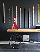 Tintin rocket on upcycled table with wheels below collection of old rulers hanging on dark wall