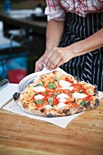 A freshly baked margherita pizza cooked in wood-fired oven
