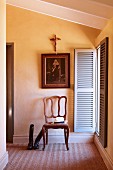 Französischer Stuhl aus Eichenholz unter religiösen Motiven neben geöffneten Fensterläden