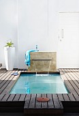 Spa area with wooden decking and sunken pool with waterfall
