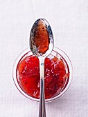 Plum and pear jam in a jar with a spoon (view from above)