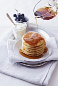 Gestapelte Pancakes mit Ahornsirup begiessen