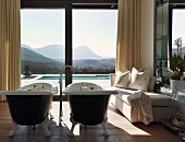 Luxuriöses Badezimmer mit zwei freistehenden, antiken Badewannen und einem prachtvollen Landschaftsblick