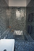 Spa atmosphere in narrow bathroom with blue and black mosaic tiles