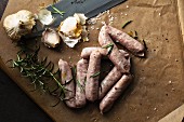 Sausages, garlic and rosemary on grease-proof paper