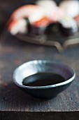 Soy sauce in a small dish in front of a plate of sushi (Japan)
