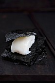 Nigiri sushi with squid (tai) between pieces of salty nori (Japan)