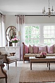 Touches of pink in comfortable living room with large soft scatter cushions on sofa and summery flower arrangements
