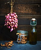 Shallots hanging up, chanterelles in a jar, and a bottle of olive oil