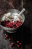 Pomegranate seeds in a metal bowl with a spoon