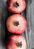 Three pomegranates on a wooden surface