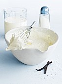 Vanilla cream in a mixing bowl with an egg whisk