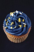 A cupcake decorated with blue icing and stars