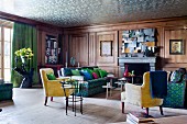 Walnut-panelled salon in blue and green combined with yellow 50s armchairs; silver reflective wallpaper on ceiling creates an illusion of height