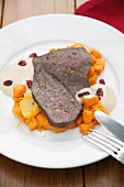 Roasted leg of venison with cranberry hollandaise and sweet potatoes cooked with orange