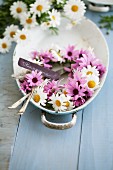 Wreath of pink and white daisies in baking dish with cutlery and name tag