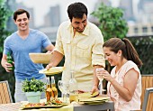 Young people setting table for barbeque in garden